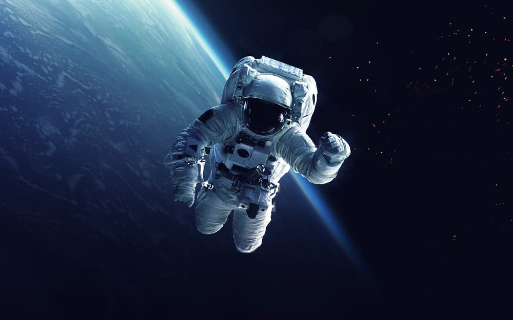 Astronaut waving in space with earth in the background