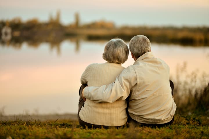 Older Couple sitting by a lake at sunset